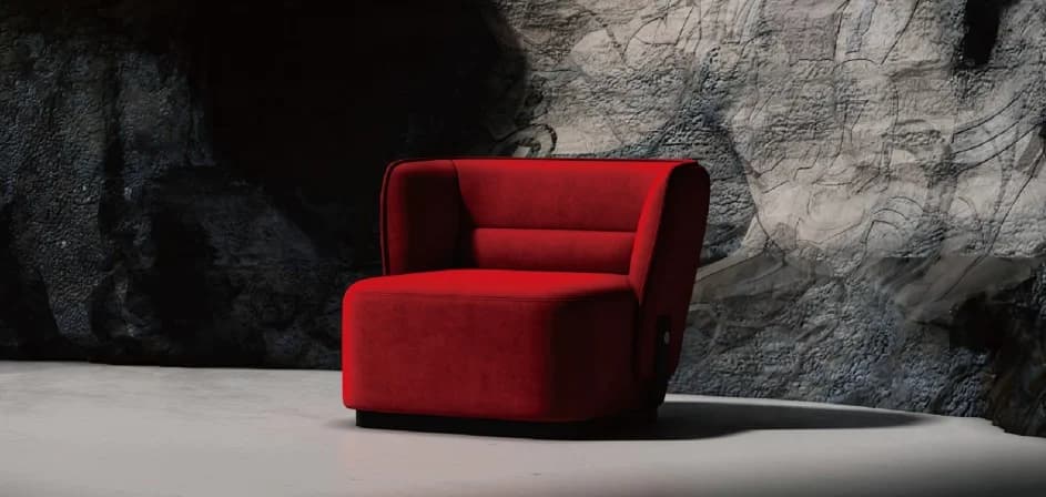 Sillón rojo de formas envolventes frente a una pared de piedra