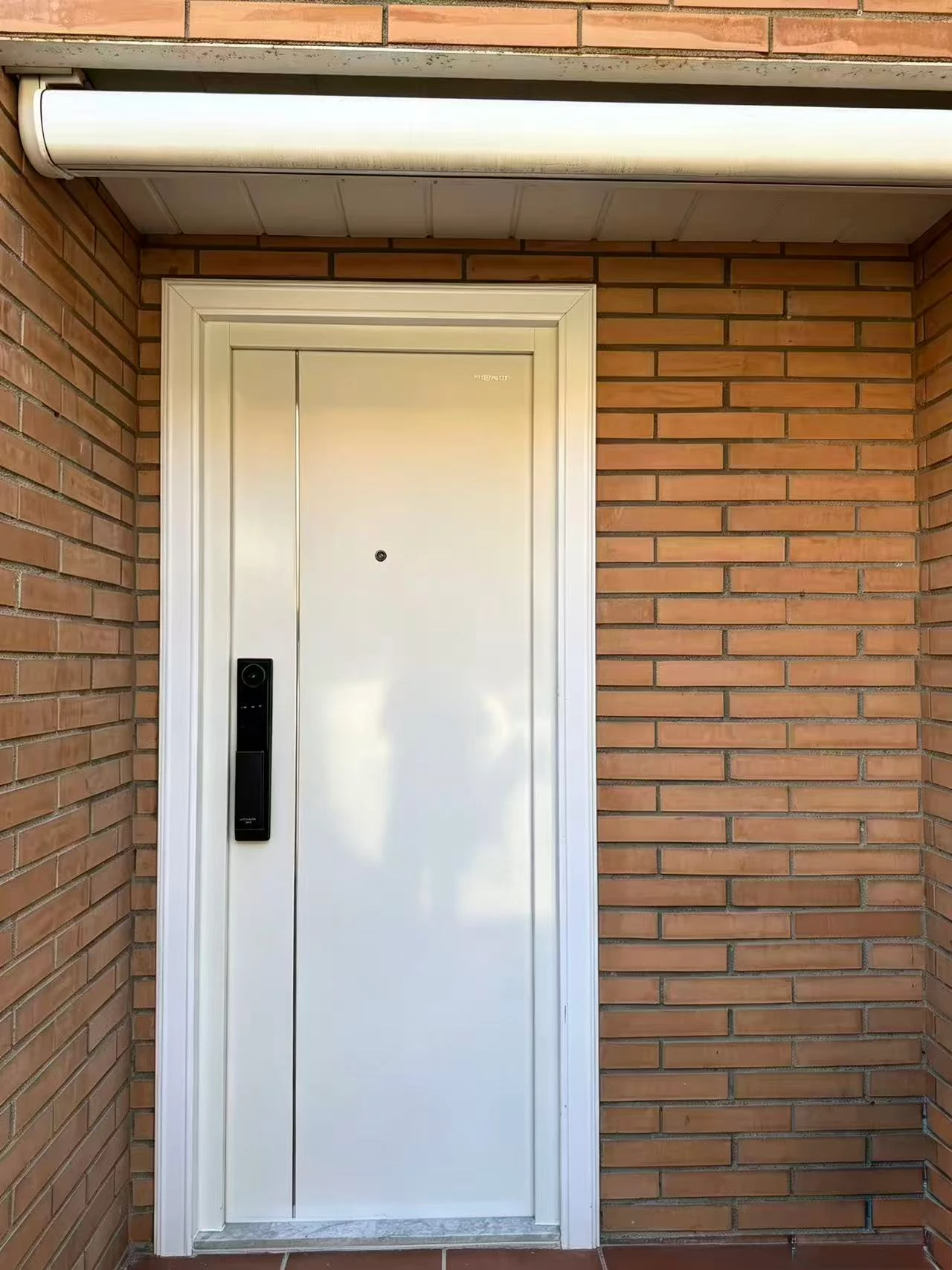 Vista exterior de la puerta y la cerradura inteligente en la fachada de ladrillo